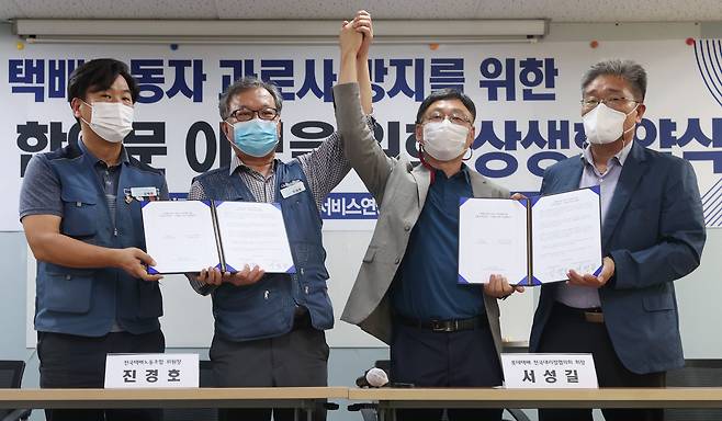 진경호 전국택배노조 위원장(왼쪽 두번째)과 서성길 롯데택배 전국대리점협의회 회장(왼쪽 세번째)이 지난 10월 서울 서대문구 서비스연맹에서 열린 소위 '상생협약식'에서 협약서에 서명한 뒤 서로의 손을 들어올리고 있다. /연합뉴스