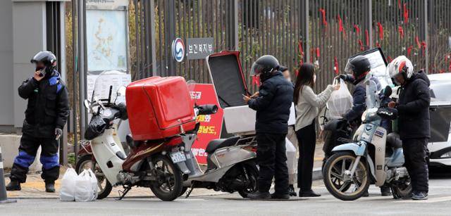 코로나19 확산세가 계속된 지난 20일 점심시간 정부세종청사 출입문에서 공무원들이 사회적 거리두기를 위해 주문한 배달 음식을 받고 있다. 세종=뉴스1