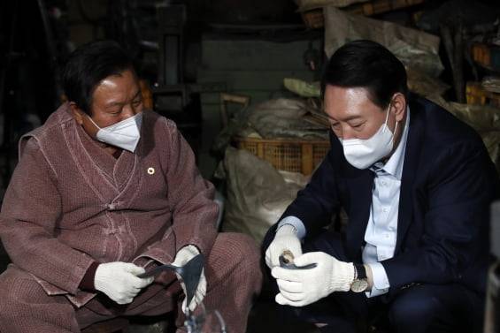 윤석열 국민의힘 대선후보가 30일 경북 영주시 영주대장간을 방문, 직접 만든 호미를 글로벌 전자상거래 업체인 아마존을 통해 판매하며 인기를 끈 'K-호미'의 주인공 석노기씨와 대화하고 있다. 2021.12.30/뉴스1