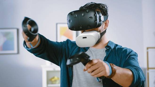 한 VR 이용자가 '뮤토크'를 입 쪽에 착용했다. 그는 VR헤드셋을 눈 쪽에 착용하고, VR컨트롤러를 손에 들고 있다. /시프톨