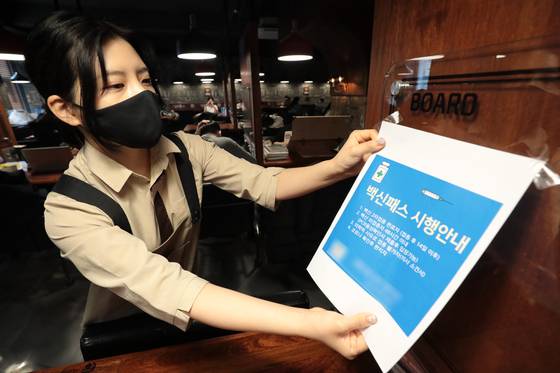 An employee takes down a notice about the vaccine pass mandate at a study cafe in Seoul on Wednesday, after the Seoul Administrative Court ruled against the measure that required adults to show proof of vaccination before entering private educational facilities. [NEWS1]