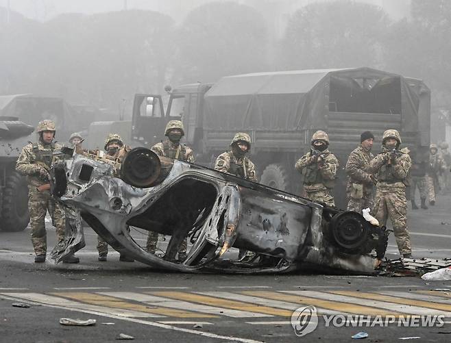 물가 폭등 항의 시위 현장 배치된 카자흐스탄군  물가 폭등 항의 시위로 비상사태가 선포된 카자흐스탄 경제 중심 도시 알마티의 도심 광장에 6일(현지시간) 군인들이 배치돼 있다. 경계 중인 군인들 앞에는 시위 과정에서 불탄 차량이 널브러져 있다. 2022.1.6 [알마티 로이터=연합뉴스 자료사진]