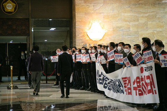 Lawmakers from the main opposition People Power Party (PPP) hold up signs at the entrance to the main chamber of the National Assembly in Yeouido, western Seoul, on Tuesday to demand an independent counsel probe into the Daejang-dong land development scandal, in which, the PPP argues, the Democratic Party presidential candidate Lee Jae-myung is involved from when he served as Seongnam mayor. [KIM KYUNG-ROK]