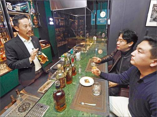 장동은 블랙바 스테이크하우스 대표(왼쪽)가 영국 영화 킹스맨을 테마로 꾸민 바에서 위스키에 대해 설명하고 있다.  신경훈 기자
