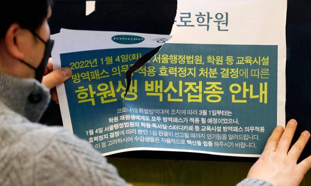 법원이 코로나19 방역패스의 효력을 일부 정지한 14일 서울 마포구 종로학원 강북본원에서 관계자가 백신접종 안내문을 떼고 있다. 이번 결정으로 12~18세 청소년에 대한 서울시 17종 시설 전부에서 방역패스의 효력이 모두 정지된다. 뉴시스