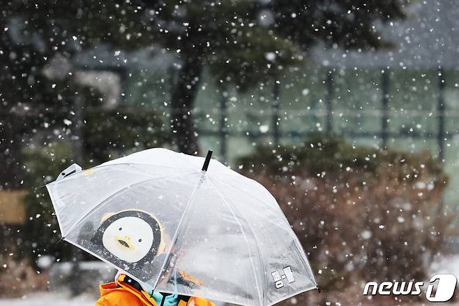 함박눈이 내린 17일 오후 서울 종로구 청와대 사랑채 앞에서 우산을 쓴 어린이가 눈을 맞으며 발걸음을 옮기고 있다. 2022.1.17/뉴스1 © News1 황기선 기자