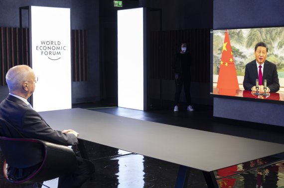 17일(현지시간) 스위스 제네바에서 클라우스 슈밥 세계경제포럼(WEF) 회장(왼쪽)이 시진핑 중국 국가주석의 화상 연설을 듣고 있다.AP뉴시스