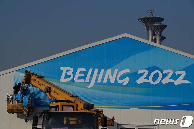 근로자가 2022년 1월 4일(현지시간) 중국 베이징 올림픽공원에 있는 건물 표지판에 현수막을 설치하고 있다. © AFP=뉴스1 © News1 김지현 기자