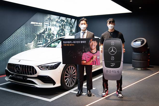 한성자동차가 운영하는 메르세데스-벤츠 서초 전시장에서 김상균 제너럴 매니저(왼쪽)와 축구선수 황희찬(오른쪽)이 지원받은 차량과 함께 기념 촬영을 하고 있다.
