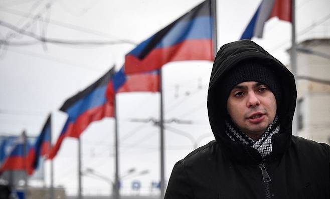 러시아의 영향권에 들어간 우크라이나 동부 도네츠크에서 18일(현지 시각) 한 남성이 나란히 걸린 러시아 국기와 도네츠크 자치공화국기 아래로 걸어가고 있다. /AFP 연합뉴스