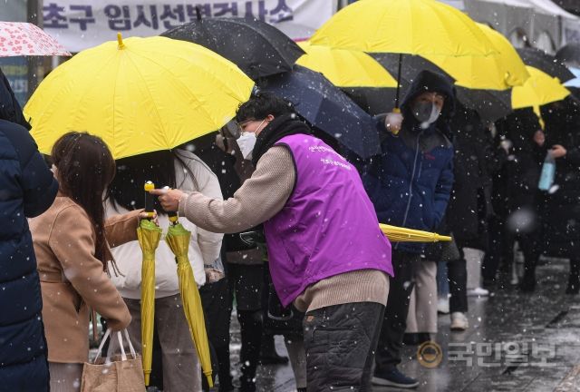 19일 서울 서초구 강남역 임시선별검사소에서 서초구청 관계자가 검사를 받기 위해 방문한 시민들에게 우산을 나눠주고 있다.