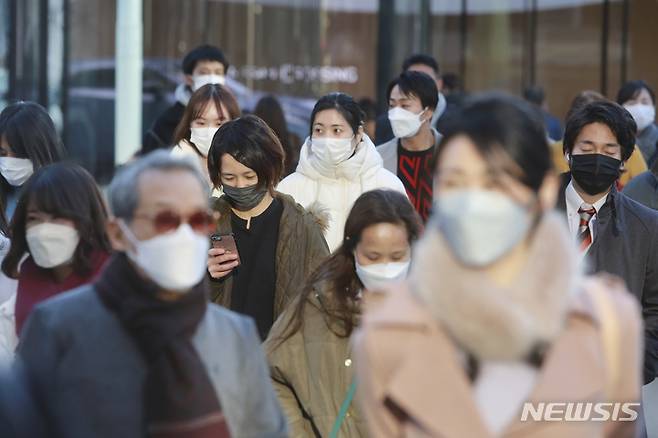 [도쿄(일본)=AP/뉴시스]지난 12일 일본 도쿄의 거리를 코로나19 감염 예방을 위해 마스크를 착용한 시민들이 걸어가고 있다. 2022.01.13.
