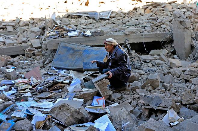 지난 18일(현지시각) 예멘 반군 후티가 장악하고 있는 수도 사나에서 한 주민이 전날 밤 사우디아라비아 주도 동맹군의 공습으로 파괴된 건물의 잔해를 뒤지며 쓸만한 물건들을 찾고 있다. /연합뉴스