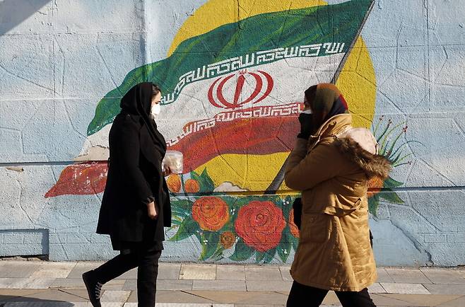 지난 22일 이란 수도 테헤란에서 시민들이 국기가 그려진 벽 앞을 지나가고 있다. 테헤란/EPA 연합뉴스