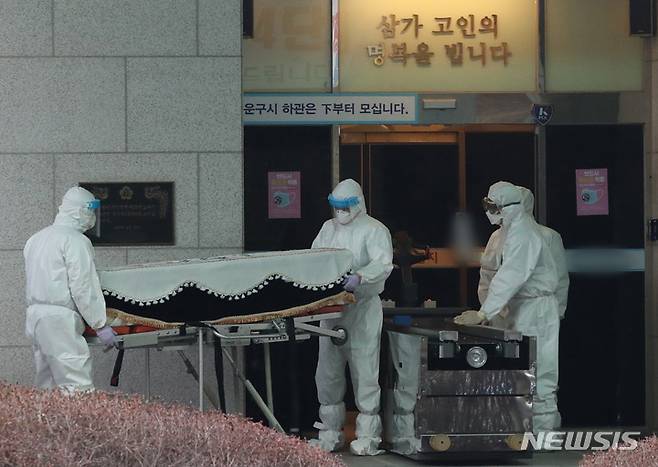 [경기=뉴시스] 김종택기자 = 22일 오후 경기도 한 화장장에서 방역 관계자들이 코로나19로 숨진 고인의 관을 화장터로 이송하고 있다. 2021.12.22.jtk@newsis.com