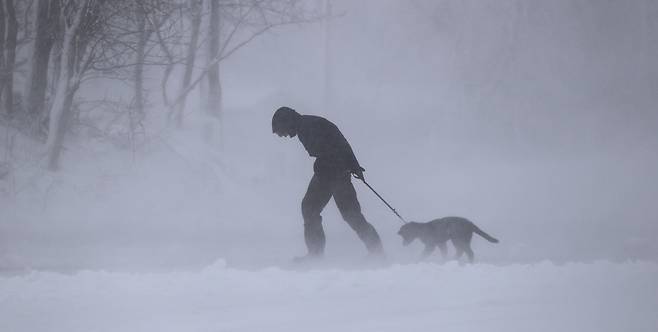 미국 매사추세츠주에서 한 행인이 눈보라에 맞서 개와 산책을 하고 있다. /EPA 연합뉴스