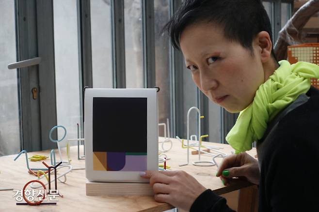 이슬기 작가가 작업실이기도 한 프랑스 파리 자택에서 그의 누비이불 작품들로 채운 2022년 리움미술관의 한정판 탁상 달력을 만지며 카메라를 보고 있다. / 이슬기 제공