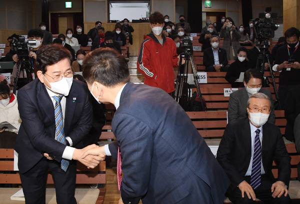 송영길 더불어민주당 대표와 김기현 국민의힘 원내대표가 10일 오후 서울 마포구 다리소극장에서 열린 김종인(오른쪽) 전 국민의힘 총괄선대위원장의 출판기념회에서 악수하고 있다. 김 전 위원장이 자리에 앉아 두 사람이 악수하는 모습을 지켜보고 있다.  국회사진기자단