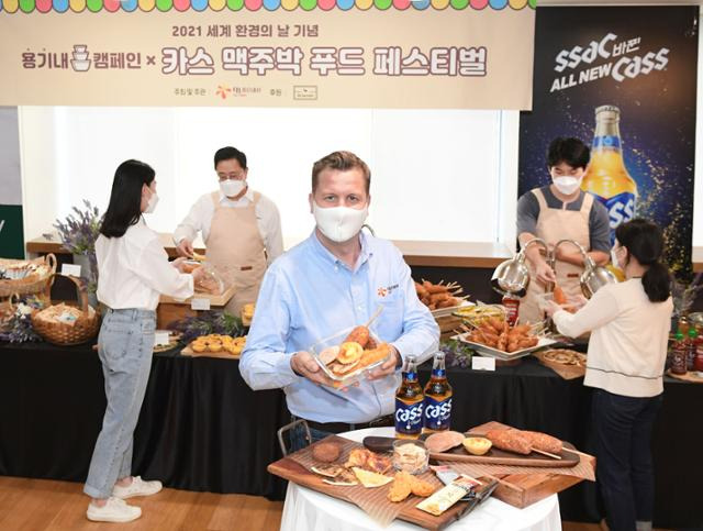 오비맥주 배하준(가운데) 대표가 지난해 6월 서울 강남구 오비맥주 본사에서 개최한 '카스 맥주박 업사이클링 푸드 페스티벌'에서 직접 챙겨온 용기에 맥주박으로 만든 음식을 담고 있다. 오비맥주 제공