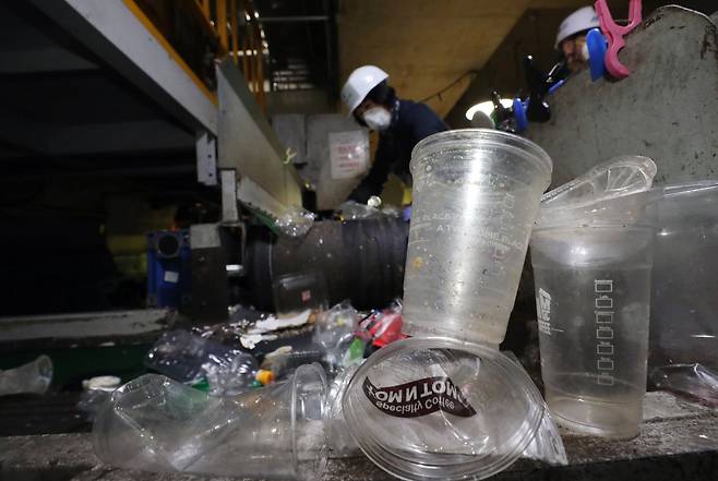 서울 구로자원순환센터에서 직원들이 일회용 플라스틱 컵 등을 분리 선별하는 모습. 뉴스1