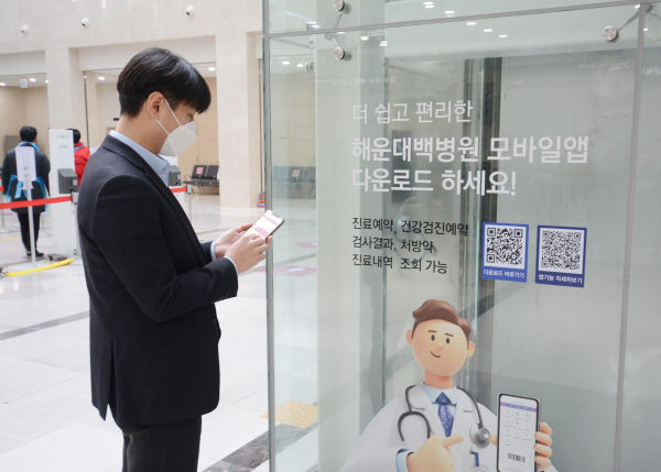 해운대백병원에서 이용객이 안내를 보며 모바일 앱을 설치하고 있다.