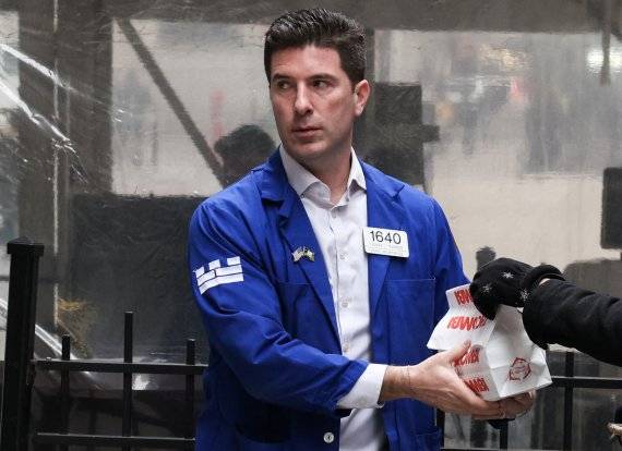미국 뉴욕 맨해튼의 뉴욕증권거래소(NYSE) 앞에서 24일 한 중개인이 배달된 점심도시락을 받고 있다. 뉴욕증시를 비롯해 금융시장은 이날 빠르게 안정을 찾았다. 로이터뉴스1