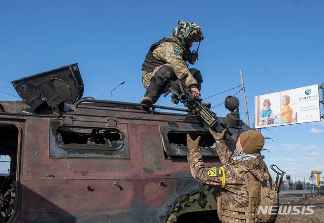 [하르키우=AP/뉴시스] 27일(현지시간) 우크라이나 하르키우에서 우크라이나 군인들이 교전 중 파손된 군 차량에서 무기를 회수하고 있다. 2022.02.28.