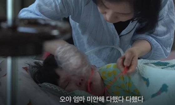 충남 아산의 강혜연씨가 희귀병을 앓는 아들 태경이(10)의 가래를 뽑아내고 있다. 강씨는 10년째 집에서 24시간 아이의 의료 처치와 돌봄을 도맡고 있다. [유튜브 캡처]