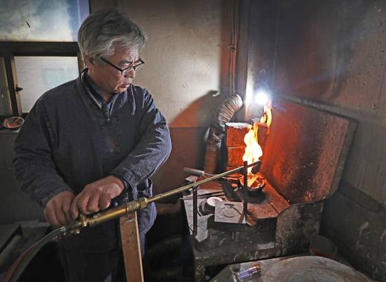 Hong melts silver to create a piece that will be attached to a kettle. [PARK SANG-MOON]