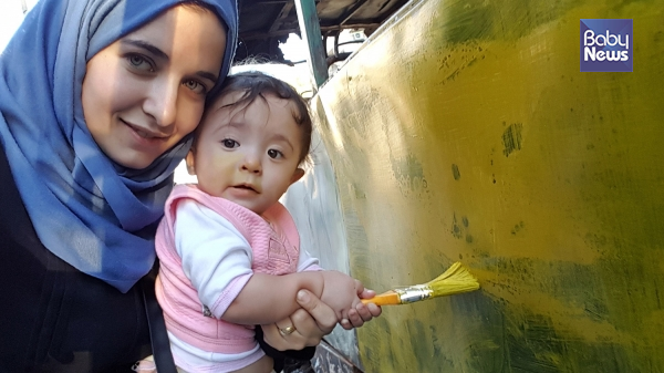 폭격을 맞고 버려진 버스를 칠하는 와드와 사마. ⓒ(주)엣나인필름