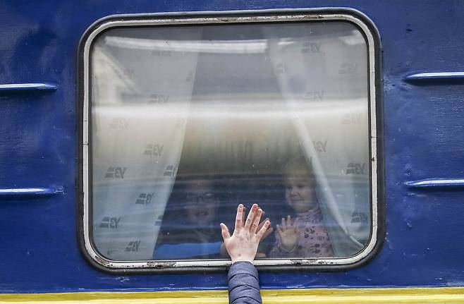 3일(현지시간) 우크라이나 키이우 역에서 한 아버지가 피난 열차에 오른 아내와 아이에게 작별인사를 하며 유리창에 손을 대고 있다. 이 열차는 키이우에서 폴란드 국경 인근 도시인 르비우로 간다. 로이터=연합뉴스