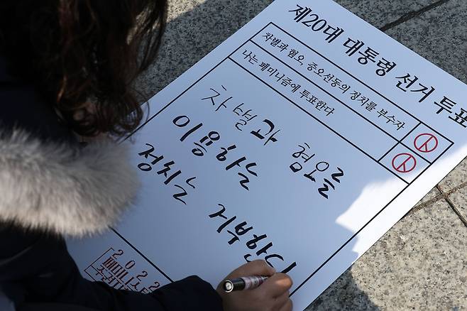 2022 페미니스트 주권자행동 회원들이 지난달 12일 서울 종로구 보신각 앞에서 '차별과 혐오, 증오선동의 정치를 부수자' 집회를 열고 메세지를 작성하는 모습. /뉴시스