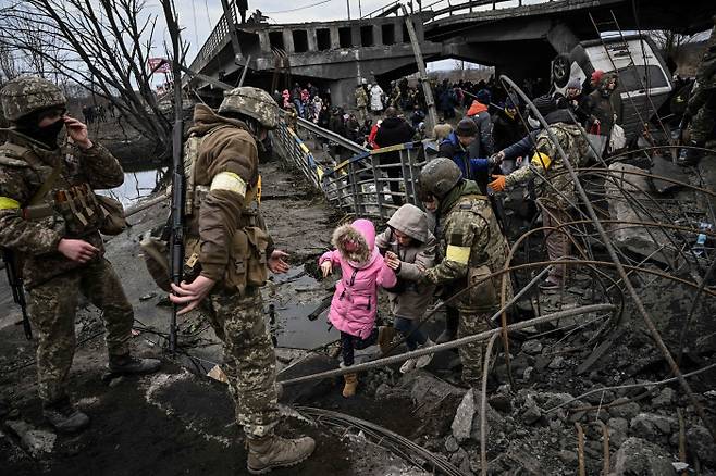 폭격으로 파괴된 키이우 북부의 도시 이르핀에서 3월 5일 피란민들이 무너진 다리를 건너고 있다.  AFP연합뉴스