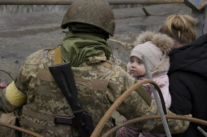 한 아기가 3월 5일 이르핀강을 건너는 걸 도와주는 우크라이나 군인을 쳐다보고 있다.  AP연합뉴스
