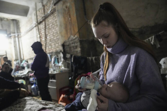 우크라이나 마리우폴의 방공호에서 3월 7일 한 여성이 아기에게 분유를 먹이고 있다.   AP연합뉴스