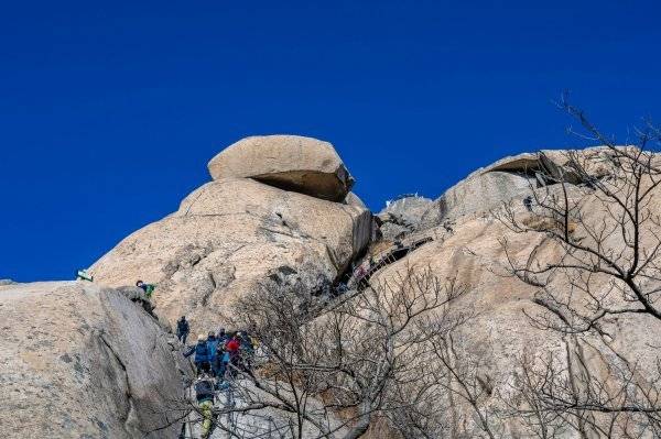 백운대 코스의 매운맛을 상징하는 암봉 구간. 가파른 길에 설치한 와이어 로프를 잡고 오르고 있다.