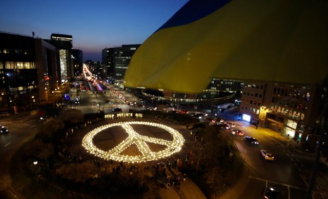 국제 시민단체인 아바즈가 22일 벨기에 브뤼셀의 유럽연합(EU) 본부 건물 앞 광장에 촛불과 전등을 이용해 평화를 의미하는 거대한 상징물을 설치했다. 우크라이나 전쟁 종식을 위해 유럽이 러시아산 원유 수입을 중단할 것을 촉구했다. 브뤼셀=EPA 연합뉴스