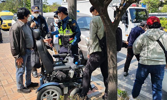 20일 서울 여의도 이룸센터 앞에서 보도블록에 낀 전동휠체어를 옮기기 위해 경찰과 시민들이 협력하고 있다.