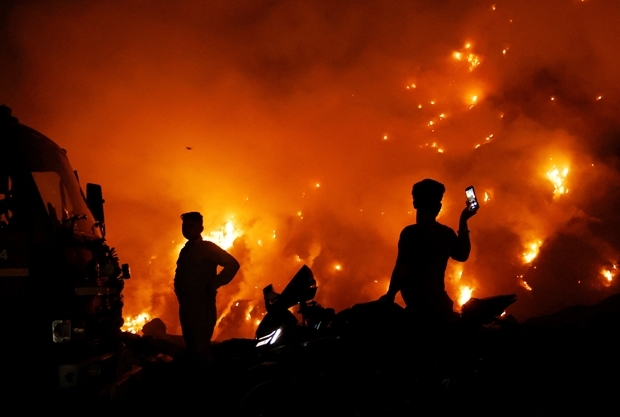 27일(현지시간) 인도 수도 뉴델리 발스와 쓰레기 매립지 화재 현장에 소방당국 관계자와 구경꾼이 모여 있다./로이터 연합뉴스