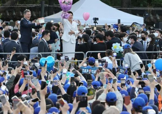 Last Present: President Moon Jae-in and first lady Kim Jung-sook thank the citizens raising a cake and flowers they received from the people who came out to greet them as they head out of Cheongwadae at the water fountain in front of Cheongwadae on May 9. Yonhap News