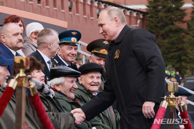 [모스크바=AP/뉴시스] 블라디미르 푸틴 러시아 대통령이 9일(현지시간) 러시아 모스크바의 붉은 광장에서 열린 제2차 세계대전 종전 제77주년(전승절) 기념 열병식에 참석해 참석자들과 악수하고 있다. 2022.05.09.