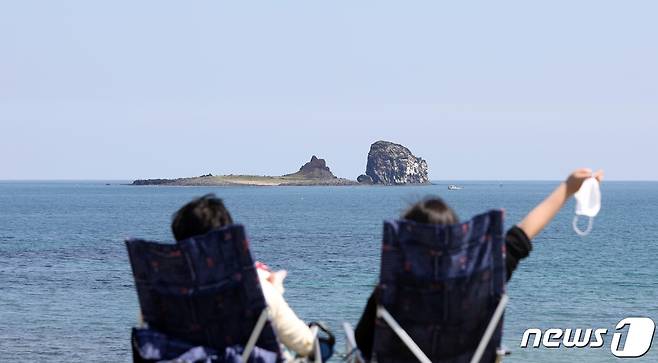 제주 서귀포시 안덕면 해안도로에서 여행객들이 간이 의자에 앉아 형제섬과 바다를 감상하고 있다.© News1 고동명 기자