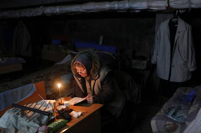 5월 10일 우크라이나 하르키우의 한 학교 지하실에 대피한 한 할머니가  촛불을 밝히고 기도를 하고 있다./로이터 뉴스1