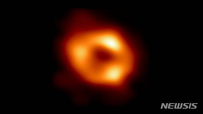 [서울=뉴시스] 인류가 사상 최초로 우리 은하 중심에 자리잡은 초대질량 블랙홀을 포착하는데 성공했다. 사진은 궁수자리 A 블랙홀. 중심의 검은 부분은 블랙홀(사건의 지평선)과 블랙홀을 포함하는 그림자이고, 고리의 빛나는 부분은 블랙홀의 중력에 의해 휘어진 빛이다. (사진=EHT 제공) 2022.05.13. photo@newsis.com