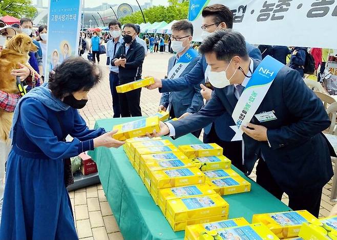 황준구 서울지역본부장이 직거래 장터 이용고객에게 고향사랑기부제 홍보 캠페인 사은품을 나눠주고 있다.