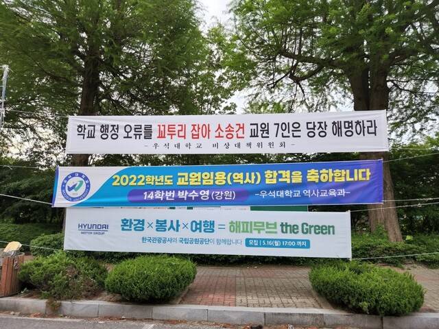 밀린 임금을 지급하라며 우석대학교 전·현직 교수 7명이 소송에서 이기자 이를 반대하는 내용의 펼침막이 대학 교정에 걸렸다. 교수들은 펼침막을 내건 ‘비상대책위원회’가 정체불명이라고 주장했다. 미지급임금소송단 제공