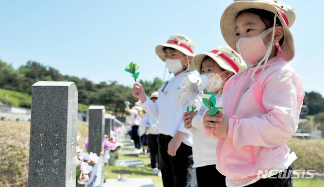 [광주=뉴시스] 이영주 기자 = 5·18민주화운동 42주기를 이틀 앞둔 16일 오전 광주 북구 운정동 국립5·18민주묘지에서 북구 양산동 인양유치원 원아들이 손수 만든 종이 꽃을 헌화하고 있다.  2022.05.16. leeyj2578@newsis.com