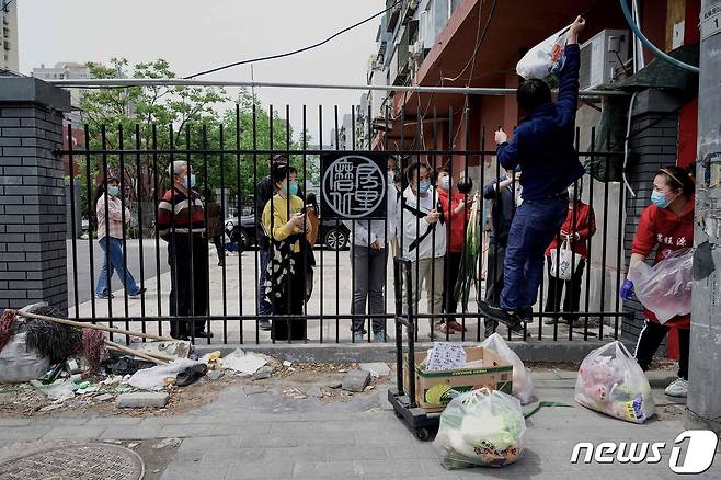 9일 (현지시간) 코로나19 봉쇄령이 내려진 중국 베이징의 주거 지역에서 배달원이 주민에게 물건을 전달하고 있다. © AFP=뉴스1 © News1 우동명 기자