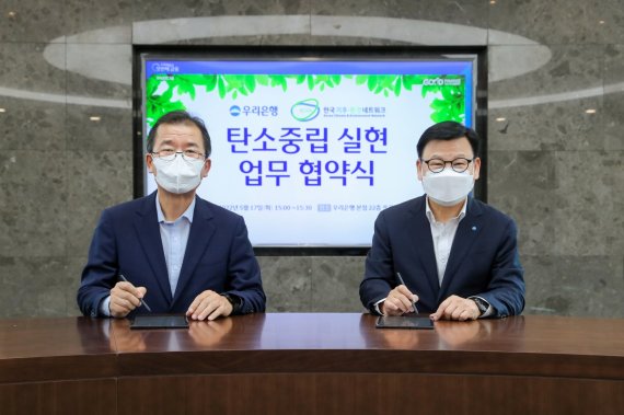 이원덕 우리은행장(오른쪽)이 지난 17일 이우균 한국기후환경네트워크 상임대표와 전자협약을 진행하고 기념촬영을 하고 있다. 우리은행 제공