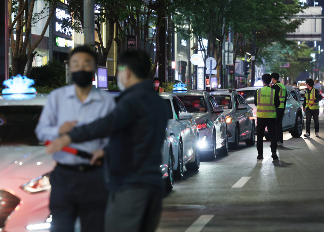 택시 기사들이 12일 밤 강남역 인근 임시 승차대에서 승객을 기다리며 대화를 나누고 있다. 연합뉴스